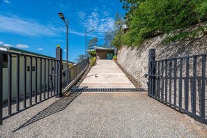 A pathway leading to a building with a metal fence on both sides, a clear sky, and a rocky hillside. - Villa Ladera Laurel 10 | Luxe Hillside Retreat with Epic Views (Potrero)