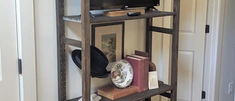 Una estantería de madera con un televisor, libros, objetos decorativos y cajas de almacenamiento.