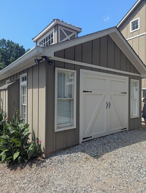 A building with a garage door, a window with blinds, and a small porch area with plants. - Peaceful and Private Studio in the Country (Canton)