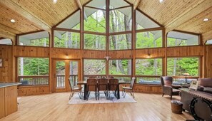 A spacious wooden interior with large windows, a dining area, and a seating area.