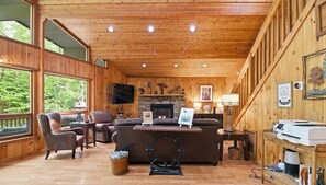 Ein Holzinterieur mit Kamin, Ledermöbeln und einem Fernseher.