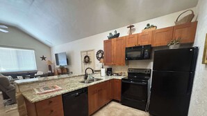 A kitchen with wooden cabinets, a black refrigerator, a microwave, and a dishwasher. - 4-BD/2-BA Southern Retreat with Waterfront Patio (Gainesville)