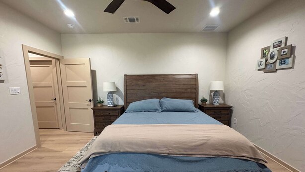 A bedroom with a bed, bedside tables, a ceiling fan, and a door. - 4-BD/2-BA Southern Retreat with Waterfront Patio (Gainesville)