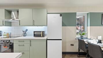 Une cuisine moderne équipée d’un four encastré, d’un four à micro-ondes et d’un réfrigérateur blanc.