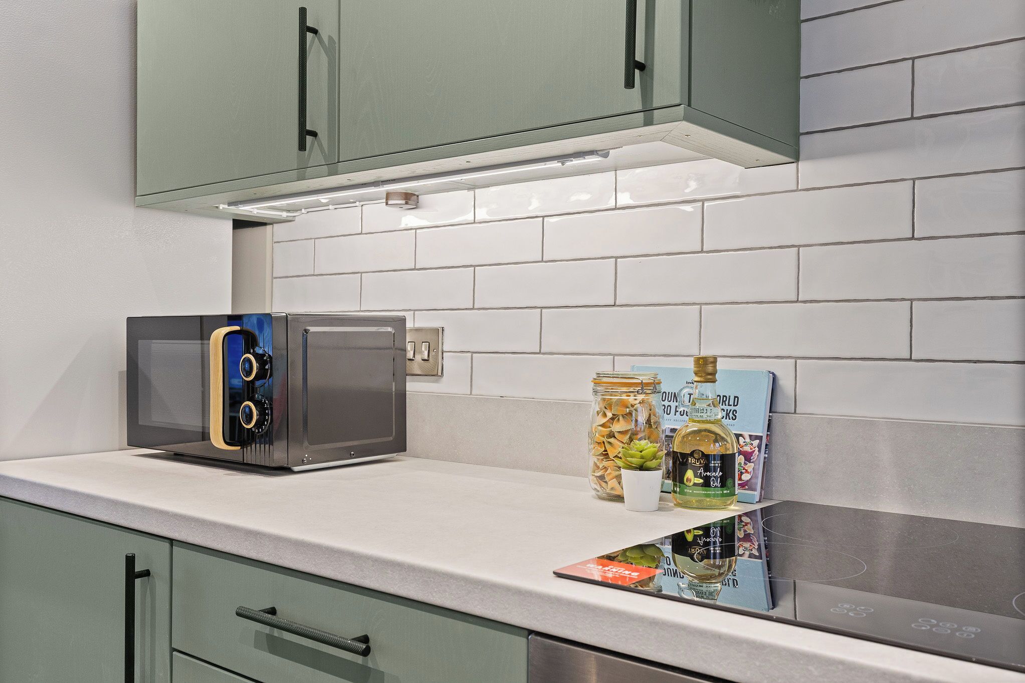 A kitchen with a microwave, a coffee maker, and a bottle of oil on the counter.