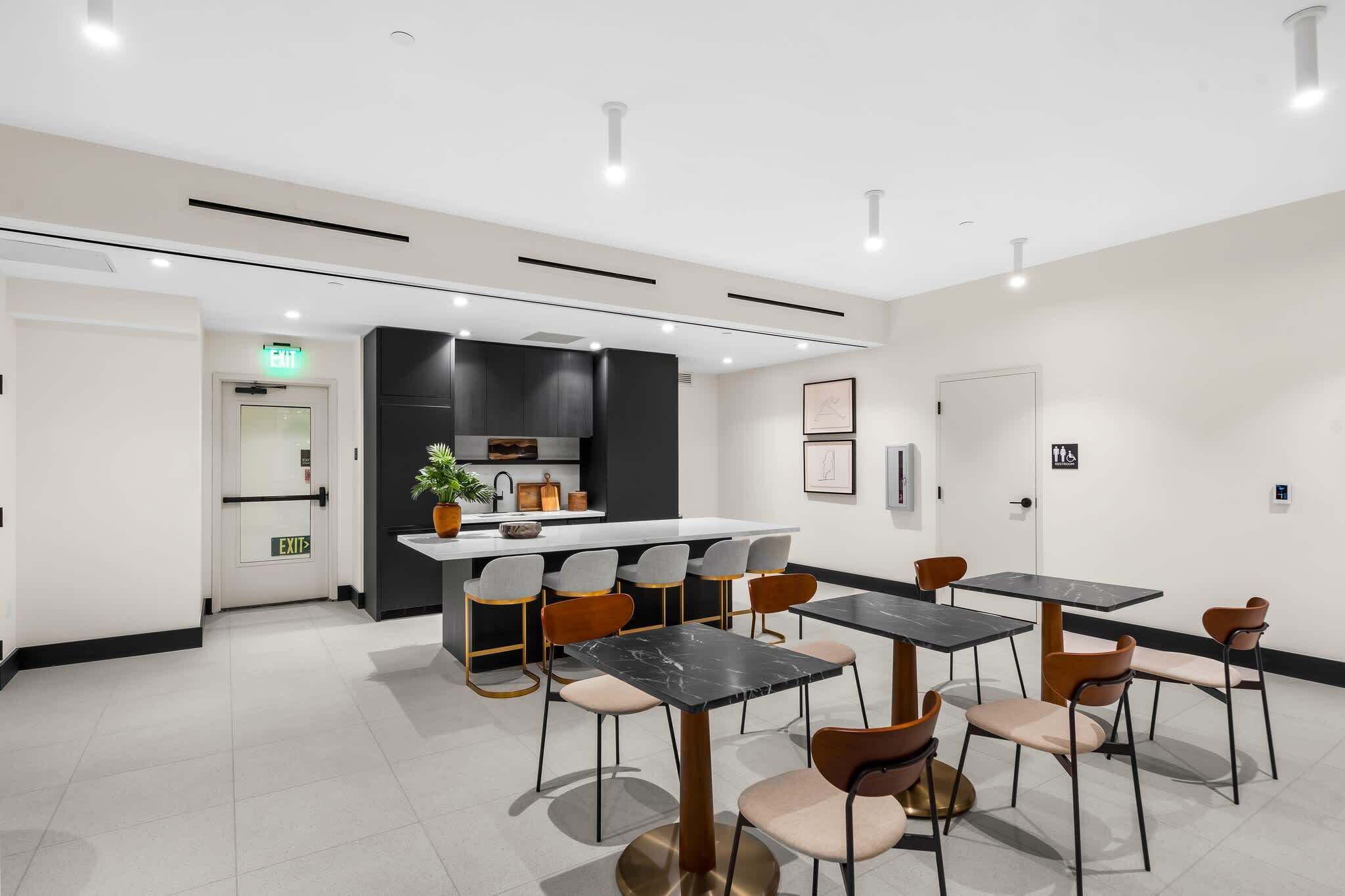 Una habitación de hotel moderna con comedor, cocina y señal de salida.