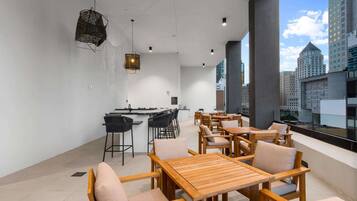 A modern interior with a bar area, seating, and large windows offering city views.