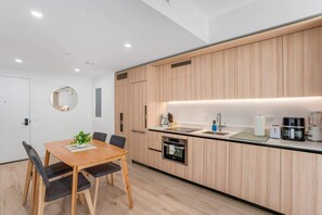 Eine moderne Küche mit Holzschränken, einem Einbauofen und einem Essbereich mit Tisch und Stühlen.