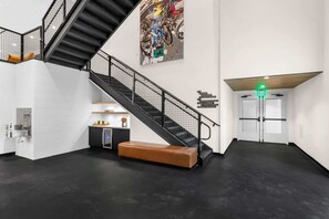 Ein modernes Interieur mit Treppe, Sitzbank, Verkaufsautomat und einer Wand mit Beschilderung.
