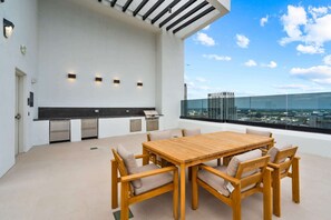 A rooftop terrace with a wooden table and chairs, a built-in grill, and a city view. - Luxury Miami 1BR Apt, Pool & Beach Access for 4 (Miami)