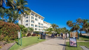 Un hôtel doté d’une cour intérieure, de palmiers et d’un panneau indiquant les équipements et services proposés.