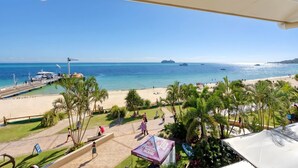 Une vue sur la plage, avec une jetée, des palmiers et un ciel dégagé.