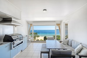 Ein Balkon mit Meerblick, einem Grill und einer Sitzecke mit Sofa und Tisch.