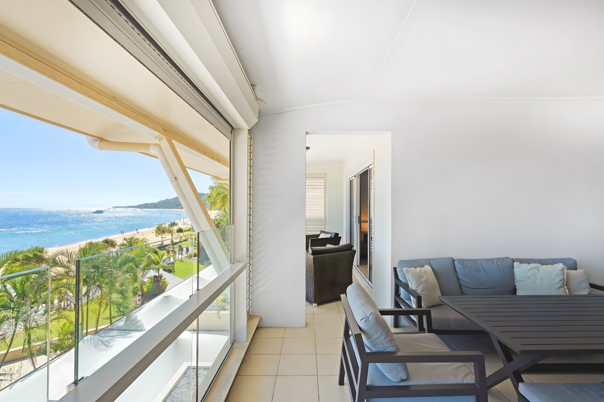 Ein Balkon mit Blick auf Strand und Meer, eine Couch und ein Tisch.