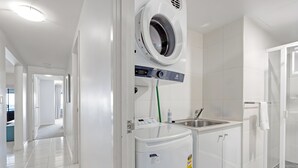 Une buanderie moderne équipée d’un lave-linge à chargement frontal, d’un sèche-linge et d’un évier.