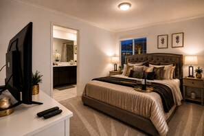 A bedroom with a large bed, bedside lamps, a TV, and a view of the bathroom. - 5-bedroom 2 MINUTE WALK TO RESORT (Davenport)