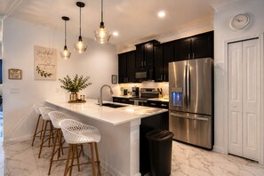 A modern kitchen with a central island, stainless steel appliances, pendant lighting, and a white tiled floor. - 5-bedroom 2 MINUTE WALK TO RESORT (Davenport)