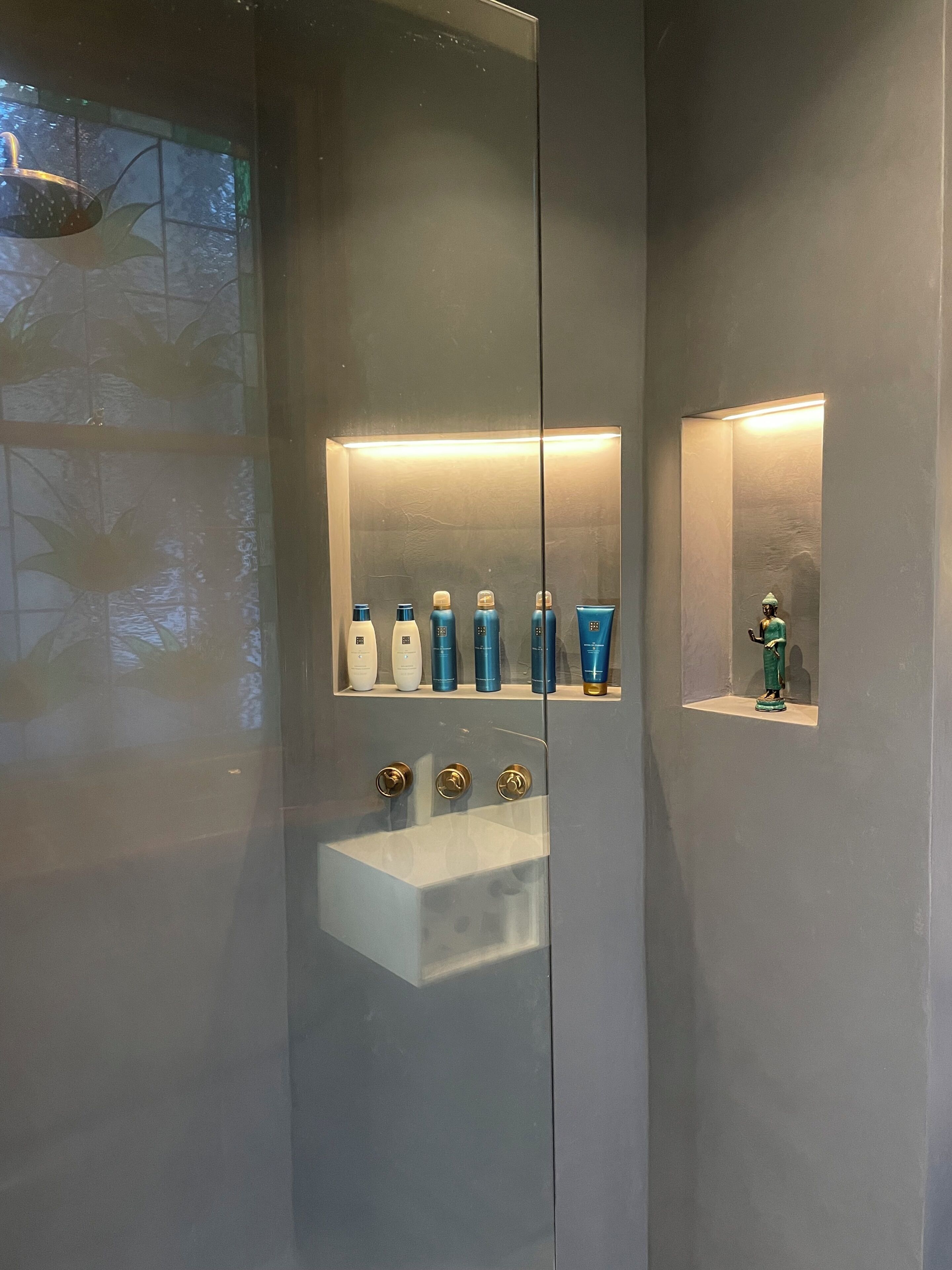 Une salle de bain avec un grand miroir, un lavabo et une étagère contenant des articles de toilette.