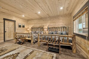 A log cabin interior with two beds, a door, a window, and a rug.
