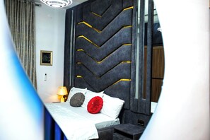 Ein Hotelzimmer mit einem Bett, einem Nachttisch, einer Lampe und einem Spiegel.