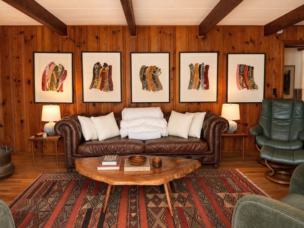 A cozy living room with a brown leather sofa, a wooden coffee table, and a patterned rug. - Boutique Riverside Retreat (Seaford)