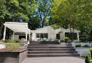 A modern house with a covered porch, a staircase leading to the entrance, and a well-maintained garden. - Boutique Riverside Retreat (Seaford)