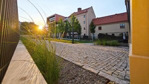 Ein gepflasterter Innenhof mit Gebäuden im Hintergrund, einem klaren Himmel und Sonnenschein.