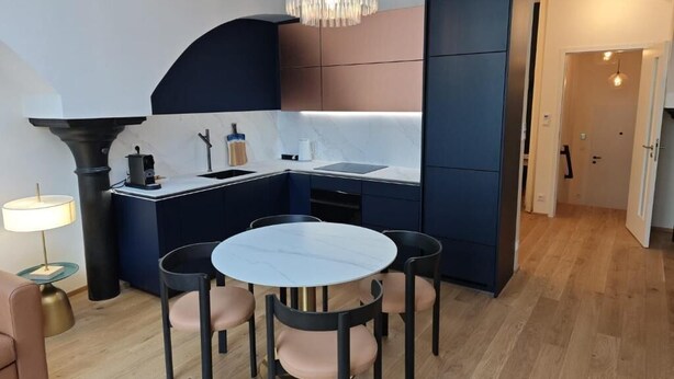 Eine moderne Küche mit Essbereich, ausgestattet mit einem runden Tisch, Stühlen, einem Backofen und einer Pendelleuchte.