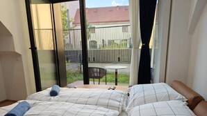 Ein Schlafzimmer mit zwei Betten, einem Balkon mit Tisch und Stühlen und Blick ins Freie.