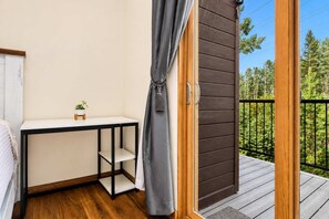 A room with a bed, a small table with a plant, a grey curtain, and a balcony with a wooden railing. - Frisco Retreat | Creekside • Unbeatable Location (Frisco)