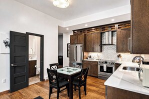 A modern kitchen with dark wooden cabinets, a glass-top dining table, and stainless steel appliances. - Frisco Retreat | Creekside • Unbeatable Location (Frisco)