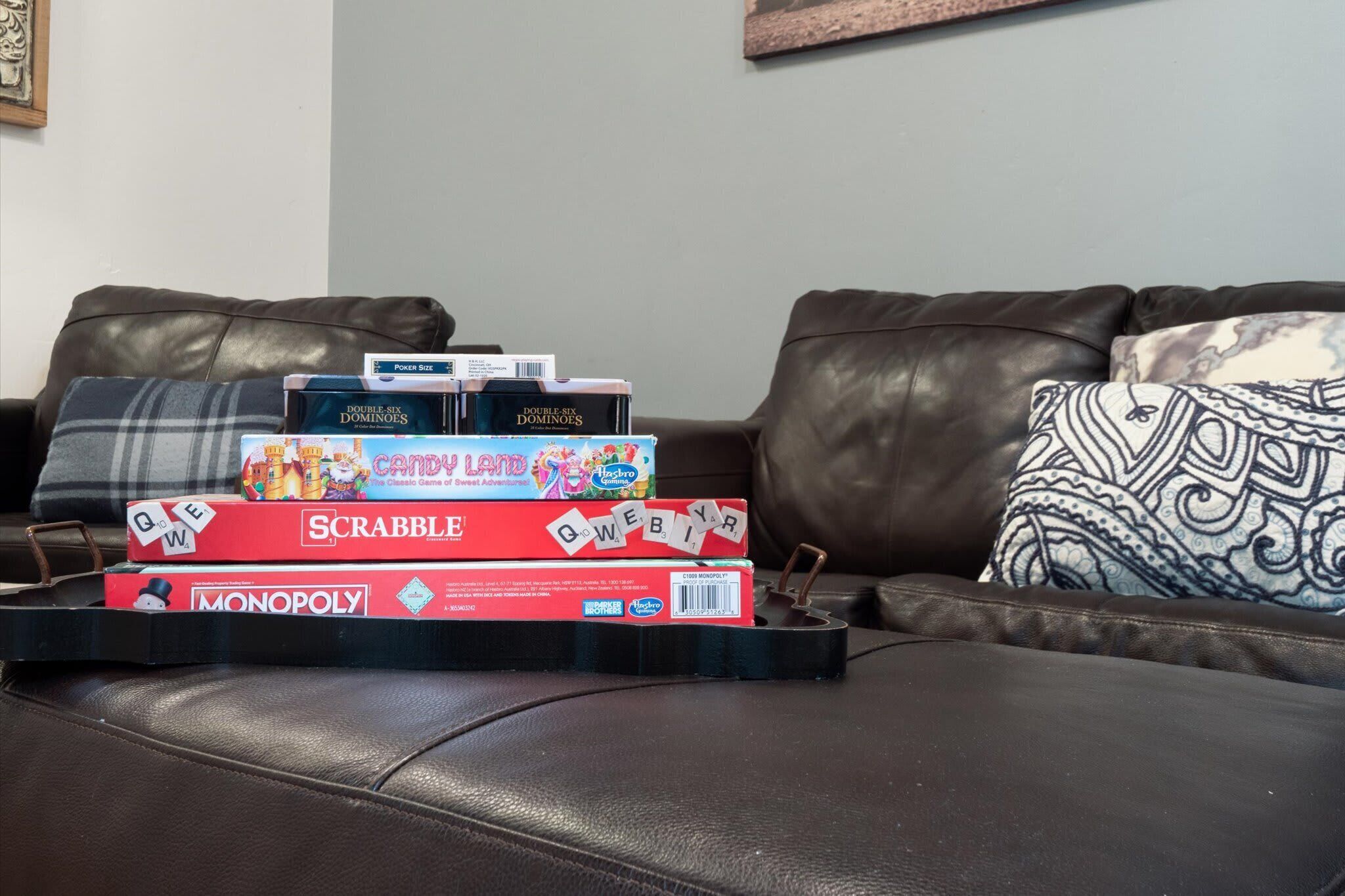 A brown leather couch with a tray holding board games.