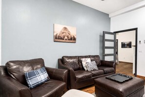 Uma sala de estar moderna com sofás de couro, uma mesa de centro e um quadro na parede.