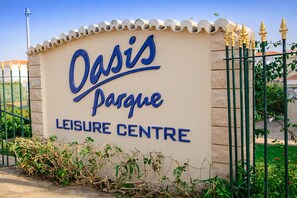 A sign for 'Oasis Park Leisure Centre' with a decorative fence and greenery in front. - Heated Indoor Pool, Jacuzzi & Tennis | Ground Floor 2BR Oasis Parque Portimao (Portimão)
