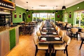 Um restaurante com várias mesas, cadeiras e um espaço de bar.