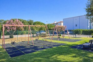 An outdoor area with a swing set, a bench, and a paved walkway. - Heated Indoor Pool, Jacuzzi & Tennis | Ground Floor 2BR Oasis Parque Portimao (Portimão)