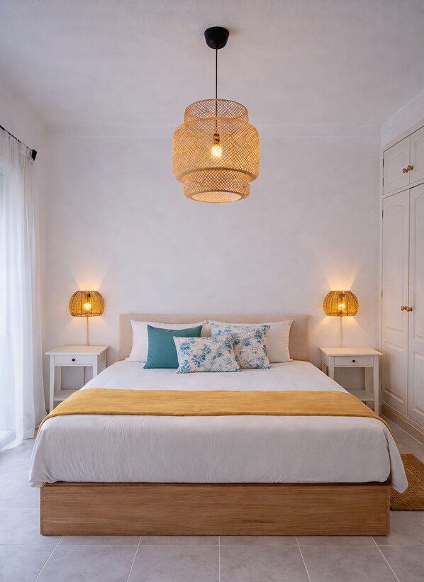 Quarto com cama, mesas de cabeceira e luminária pendente.