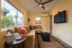 Ein Wohnzimmer mit einer Couch, einem Couchtisch, einem Fernseher und einem Deckenventilator.