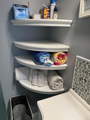 A bathroom with white shelves holding towels and toiletries. - Charming 1-bedroom craftman cottage + bikes + AC 3 blocks from beach (San Diego)