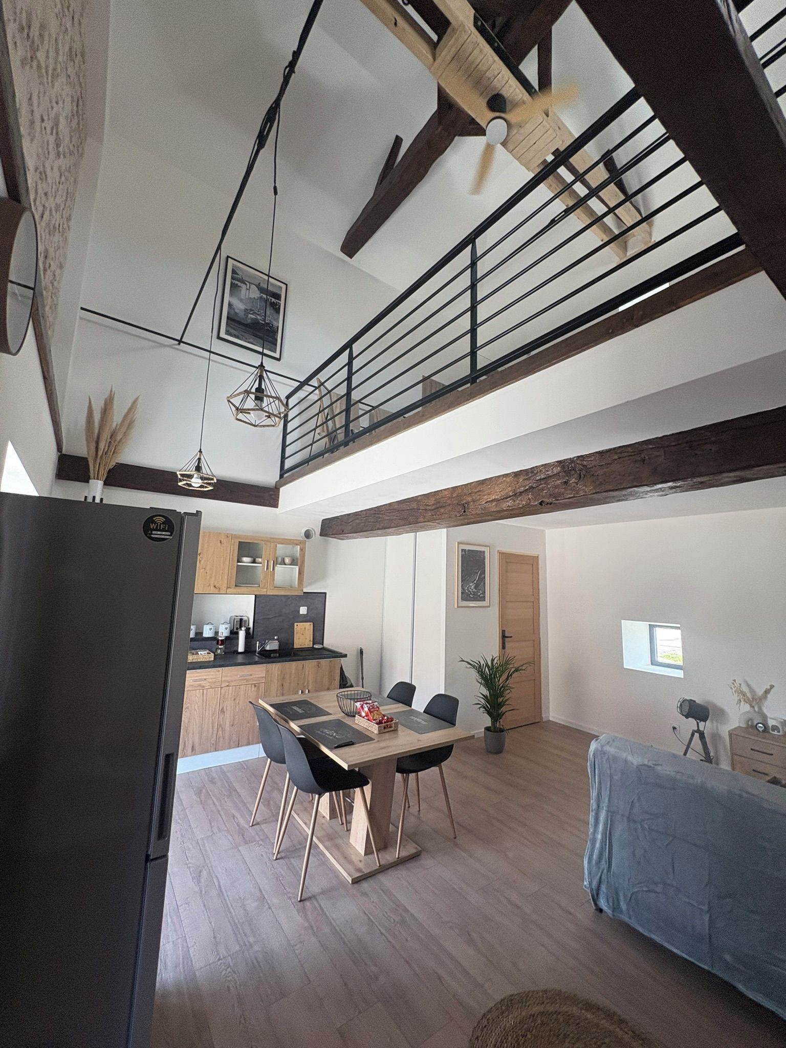 Una cocina moderna con comedor, suelo de madera y un altillo con balcón.