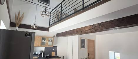 Une cuisine moderne avec un coin repas, un plancher en bois et un espace en mezzanine doté d’un balcon.