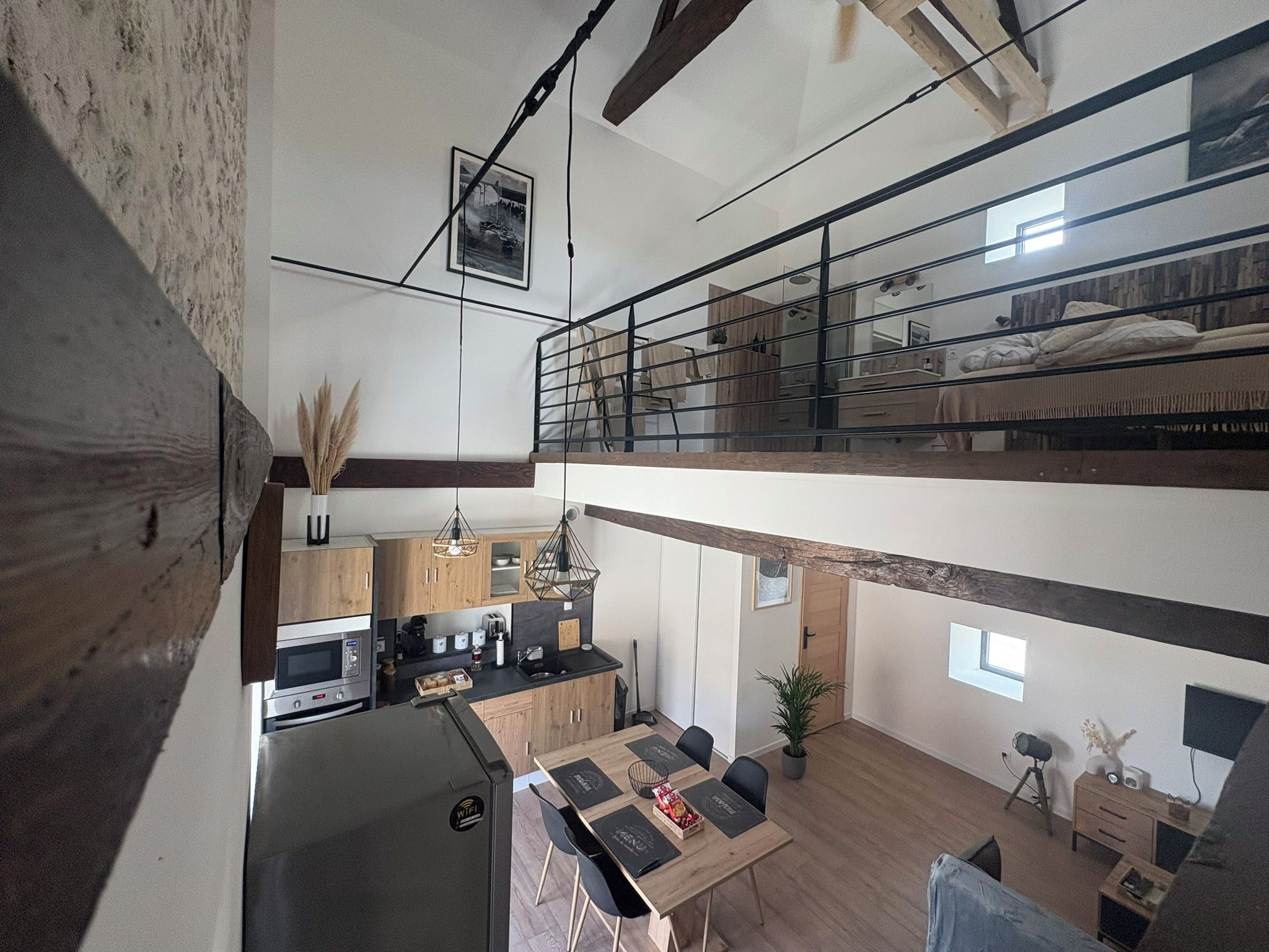 Un appartement moderne de style « loft », comprenant une cuisine, un coin repas et une chambre située en mezzanine avec balcon.