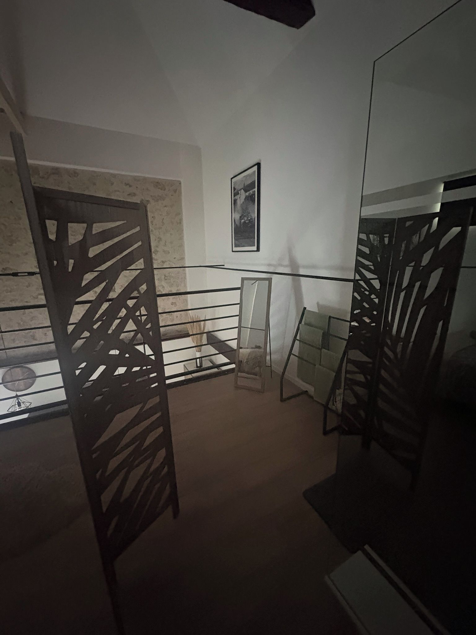 Une pièce avec un mur recouvert de miroirs, un tableau encadré et une cloison en bois.