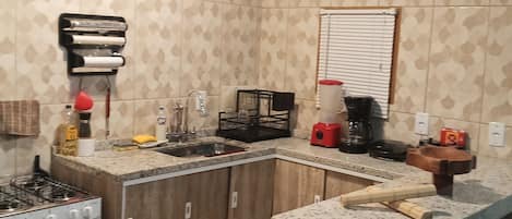 A kitchen with a gas stove, wooden cabinets, a sink, and a countertop with various items.