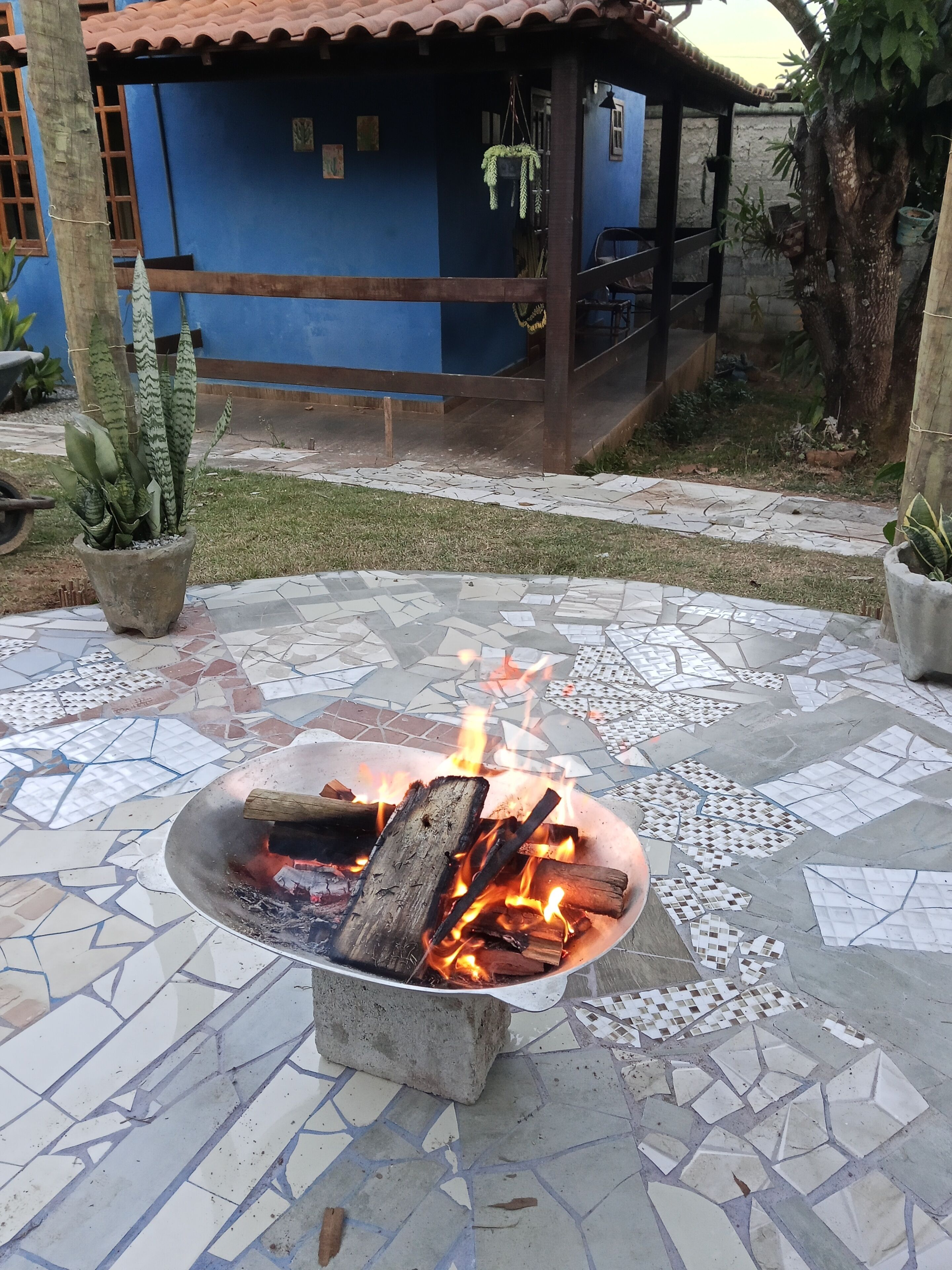 A fire pit with burning logs on a tiled patio.