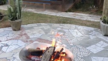 A fire pit with burning logs on a tiled patio.
