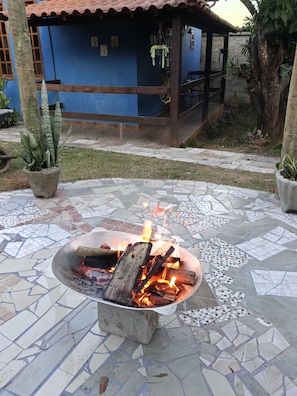 A fire pit with burning logs on a tiled patio.