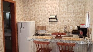 Une cuisine avec un plafond en bois, des carreaux décoratifs, un réfrigérateur, un évier, une machine à café et deux tabourets de bar en bois.