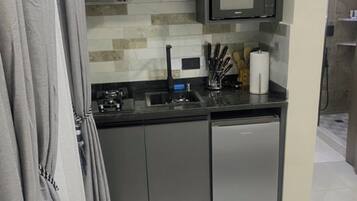 Una kitchenette compacta con microondas, pileta y alacenas.
