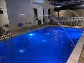 En pool med en vattenfontän, ett avslappningsområde med sittplatser och en täckt uteplats.